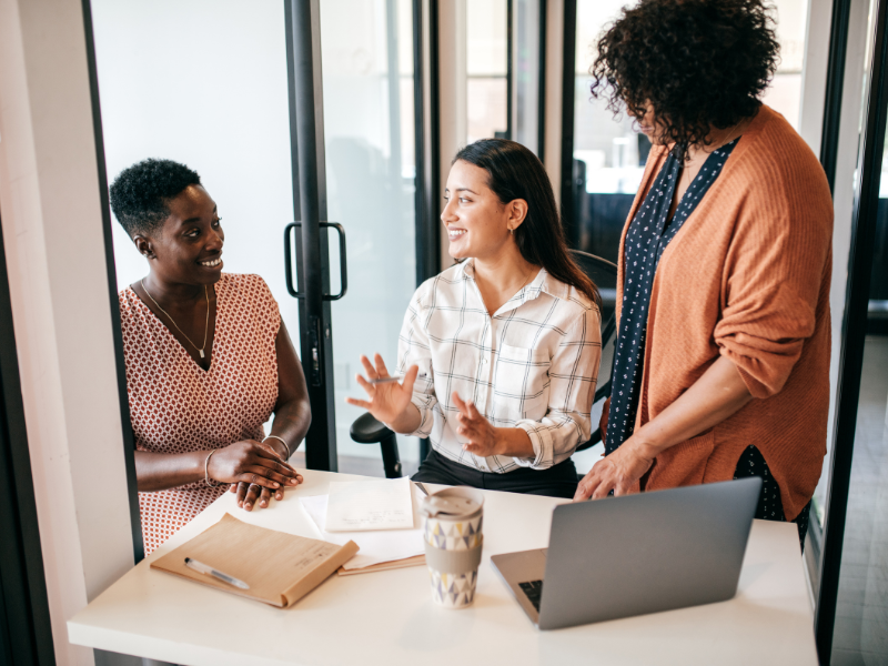Three women talking at a desk