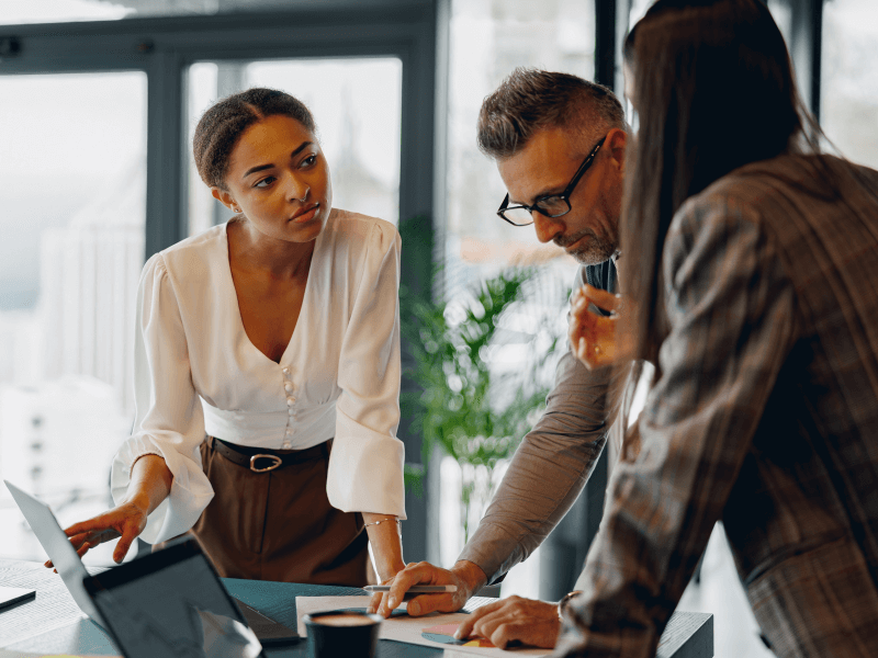 Three people collaborating at a table in an office environment.