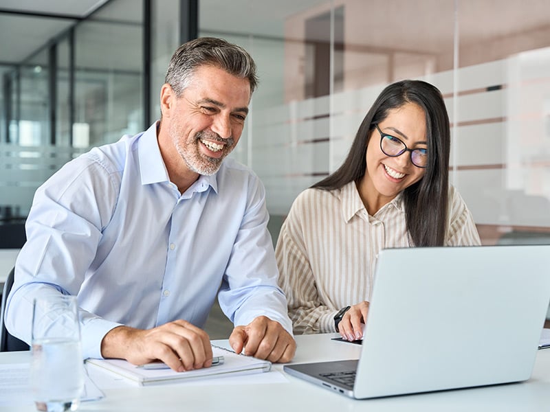 Two employees collaborating on a laptop