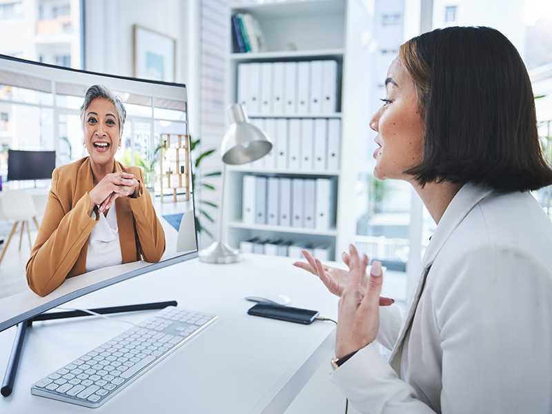 Two employees having a conversation over computer