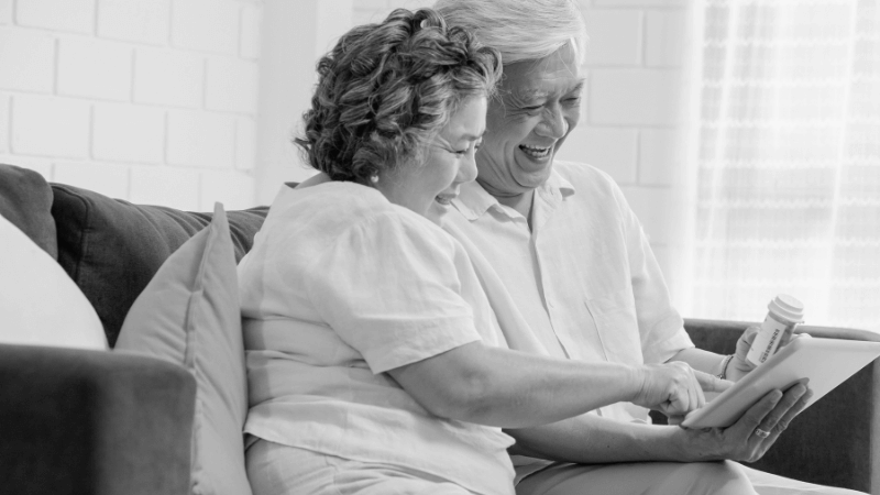 Elderly couple sitting on the couch and reviewing presecription information
