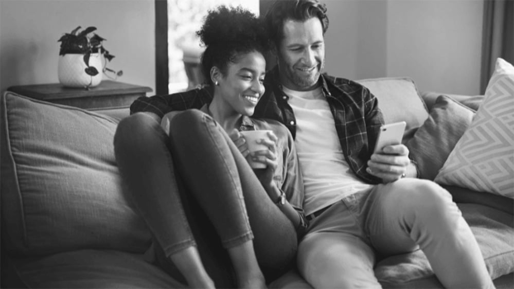 Happy young couple using a digital tablet while relaxing on a couch in their living room at home Happy young couple using a digital tablet while relaxing on a couch in their living room at home