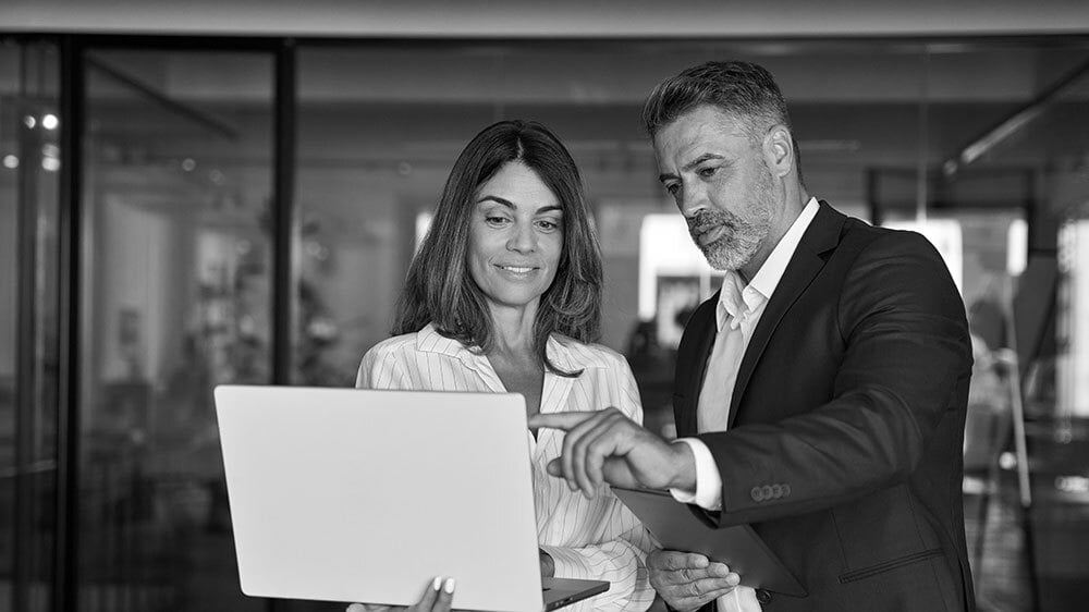 Two senior consultants review a client's customer experience strategy together on a laptop, aligning on data-driven recommendations.