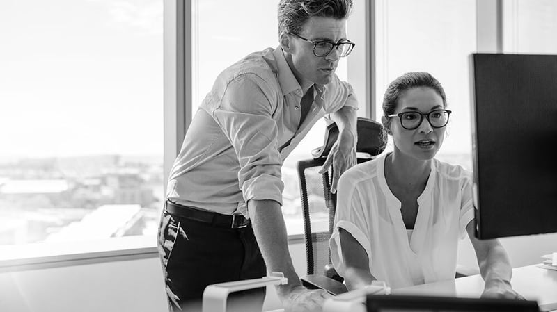 Two corporate professionals are working together on a computer.