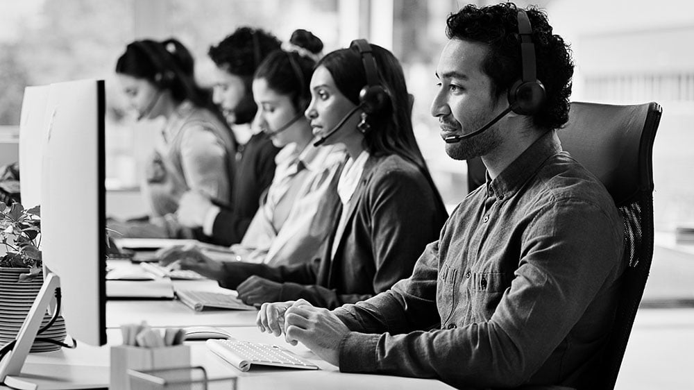 A diverse customer service team actively handling client interactions at their workstations.
