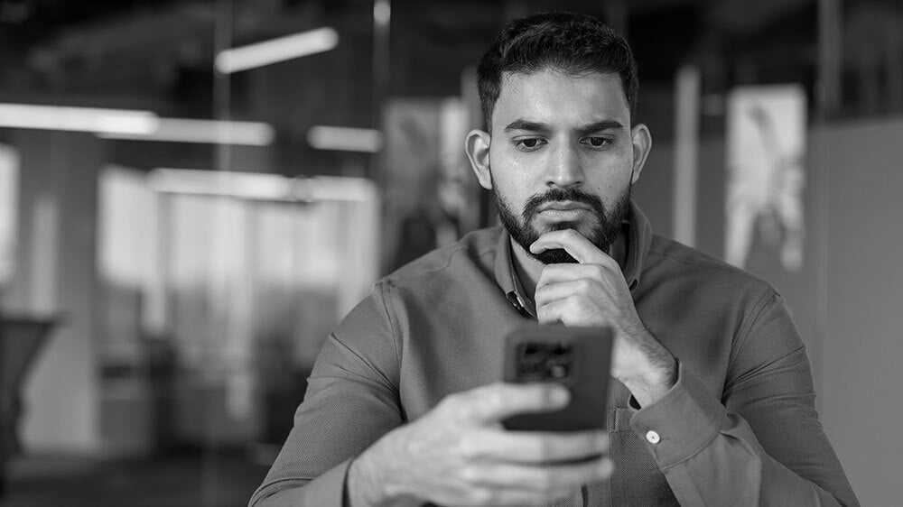 A focused man carefully service data on his mobile phone.