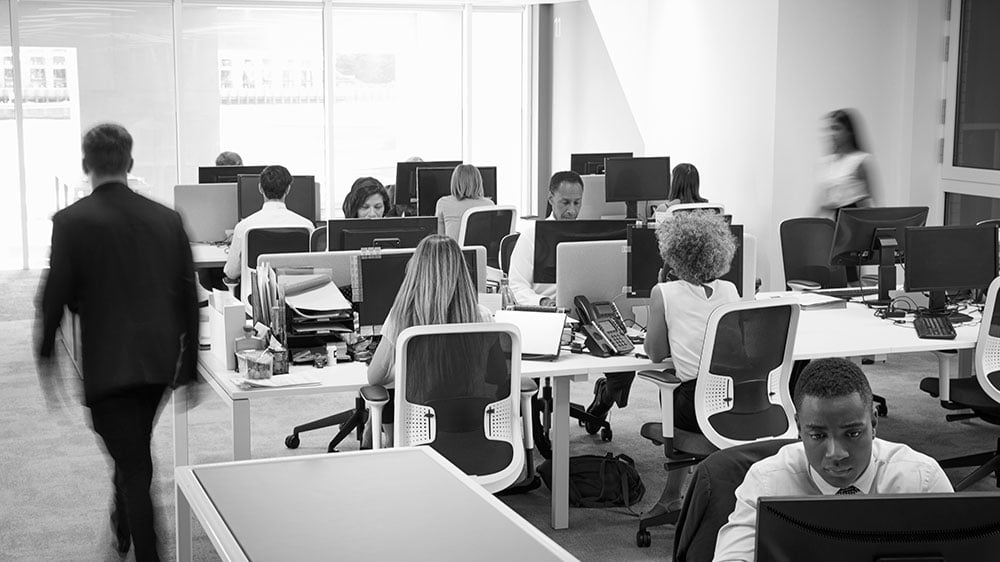 A man walking through a busy open-plan office.