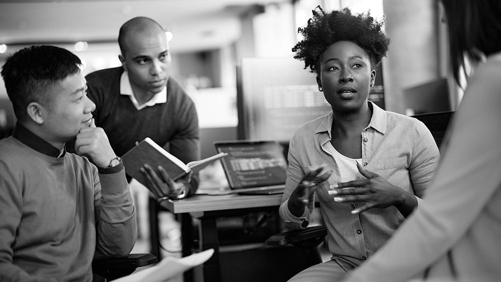 A diverse team of consultants engaged in a collaborative working session, synthesizing findings to shape a customer-centric strategy for the client.