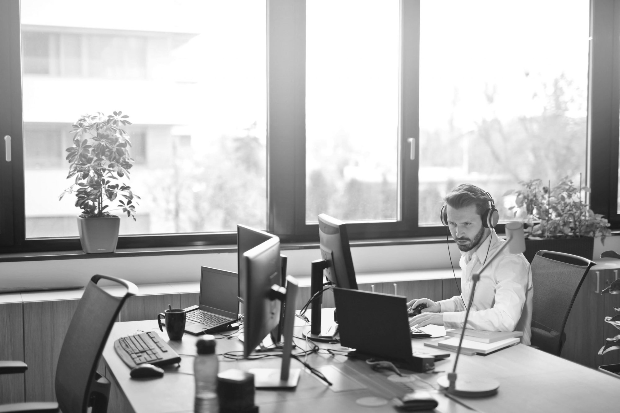 Man looking at computer screens with headset in office 