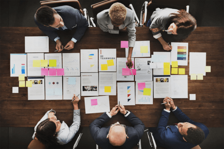 A group of business people sitting around a table analyzing project documents