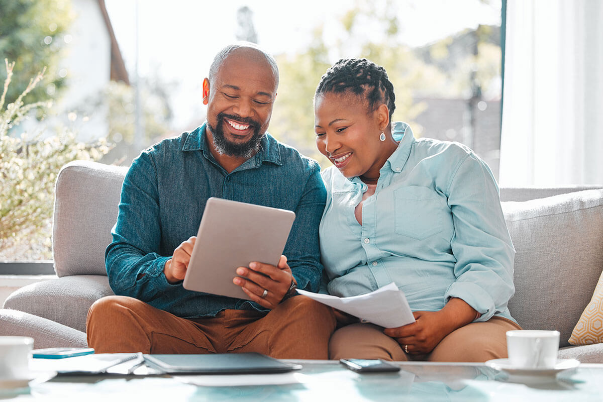 A married couple with a tablet and documents reviewing their insurance.