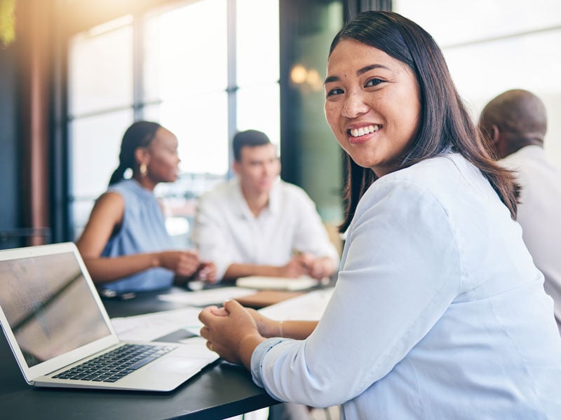 A team member smiling at the camera during a meeting in a conference room