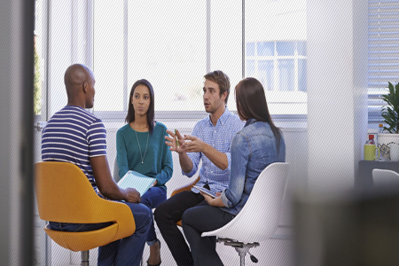 Four people sitting in a circle talking to each other