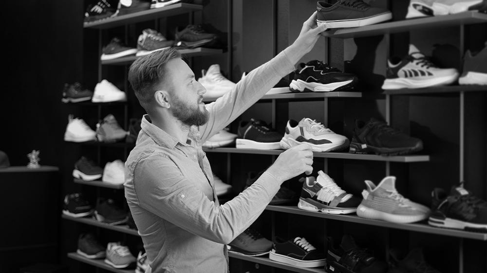 Man choosing sports shoes for running standing in the modern sportswear shop