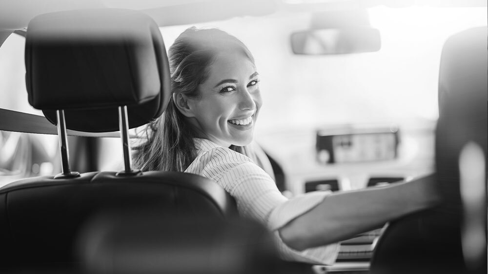 Woman smiling from the driver seat of her car