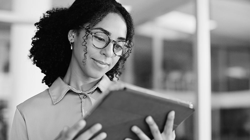 Woman with glasses reading document on digital tablet