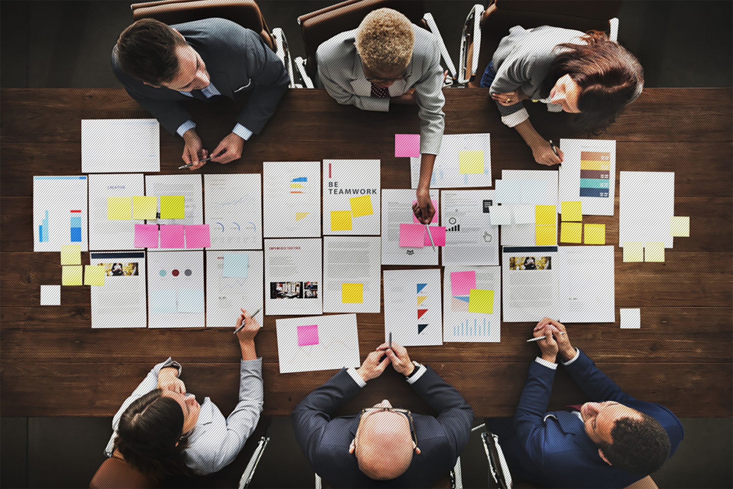 Featured image: A group of business people sitting around a table analyzing project documents - Read full post: Getting Started with Journey Analytics