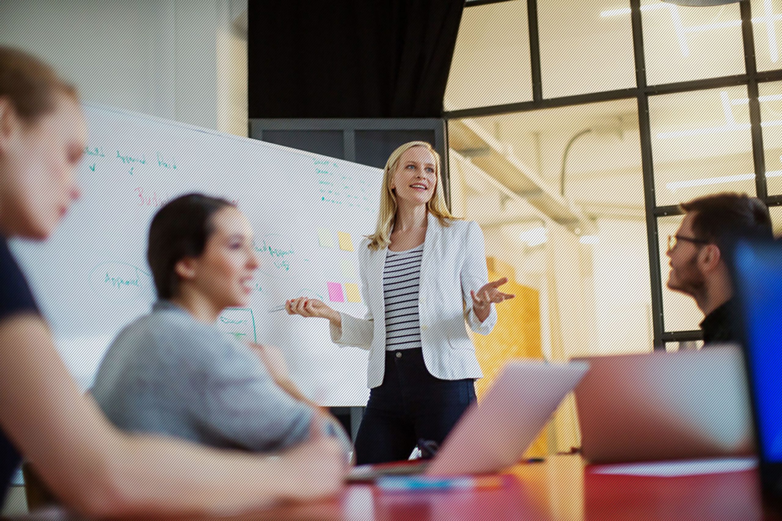 Featured image: Business woman standing at a whiteboard leading a meeting - Read full post: Why Organization Engagement is Key to Your CX Transformation